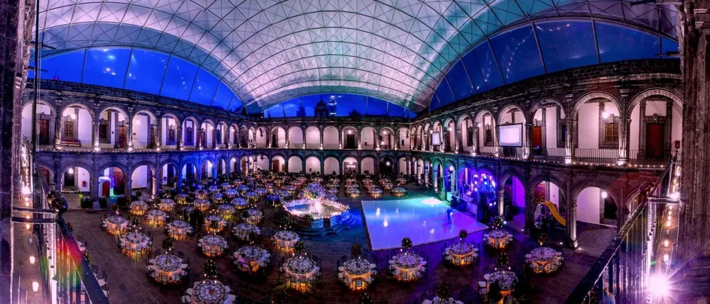 Recinto de gala con mesas montadas, iluminación y pista de baile